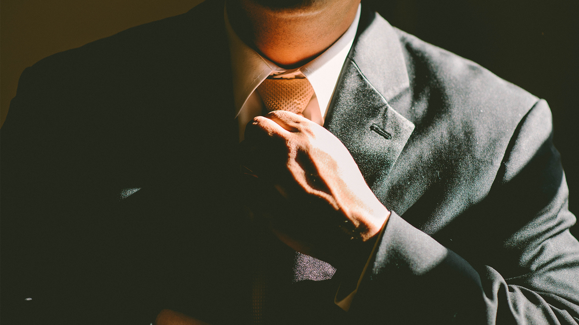 Man in suit tightening tie